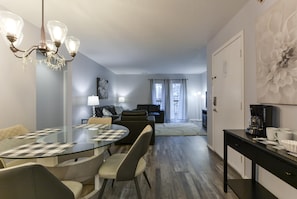 Relax in this stylish living area with a glass-top dining table, comfortable sofa, and abstract artwork.