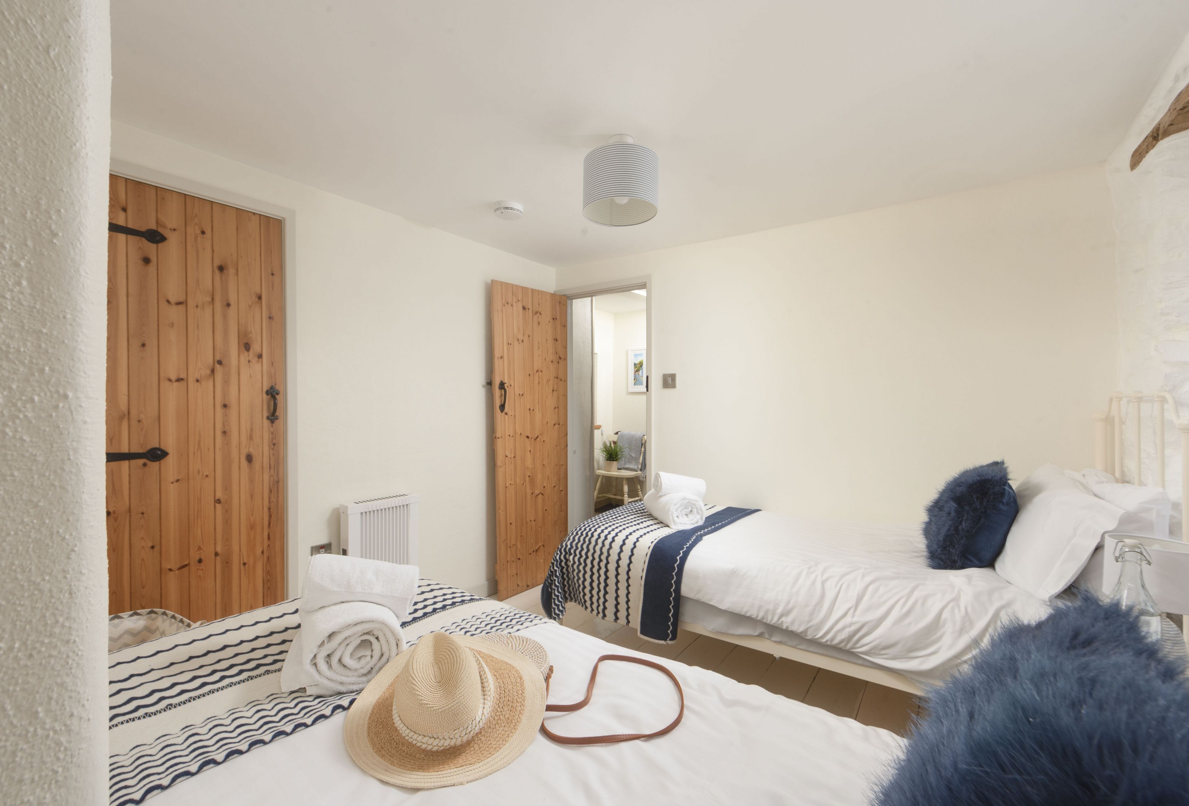 A bedroom with two beds, a wooden door, a radiator, and a mirror.