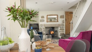 A cozy living room with a stone fireplace, a wooden staircase, and modern furniture. - Traditional cosy cottage which lies in the heart of St Agnes (St Agnes)