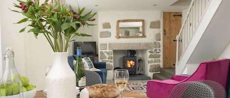 A cozy living room with a stone fireplace, a wooden staircase, and modern furniture.