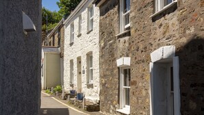 A narrow street with stone buildings, some with white window frames and shutters. - Traditional cosy cottage which lies in the heart of St Agnes (St Agnes)
