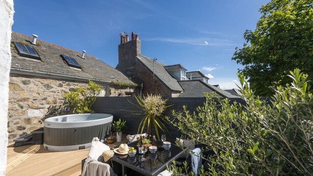 Une maison en pierre dotée d’un jacuzzi, d’un espace salon extérieur et d’un jardin.
