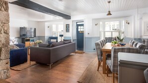 Un vaste espace de vie comprenant un canapé foncé, une table à manger avec des chaises et un mur en pierre.