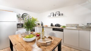 Eine moderne Küche mit weißen Schränken, einem Holztisch und einem Blumenstrauß.