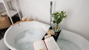 Eine Badewanne mit einem Buch, einem Schwamm und einem Glas Wasser.