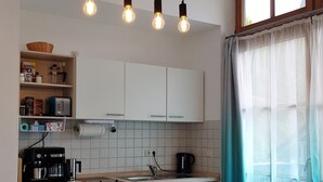 Ett modernt kök med vita skåp, diskmaskin, kaffemaskin och en matplats med bord och stolar.