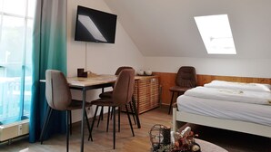 Ett rum med en säng, ett skrivbord, stolar, en tv och ett takfönster.