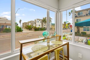 A room with large windows offering a view of a street with buildings and palm trees. - Beach-2-Bay 2br | Beach | AC | Patio (San Diego)