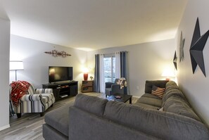 A modern living room with a grey sofa, a television, and a coffee table. - Patriot Place (Branson)