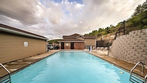 A rectangular swimming pool with a no diving sign, surrounded by buildings and a stone wall.