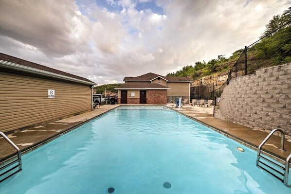 A rectangular swimming pool with a no diving sign, surrounded by buildings and a stone wall. - Patriot Place (Branson)