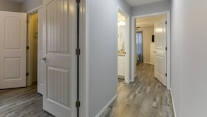 A hallway with white doors and a wooden floor.
