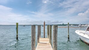 A wooden pier leading into calm waters with a boat docked on the right.