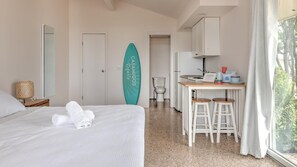 A hotel room with a bed, a bathroom, a kitchenette, and a view of trees.
