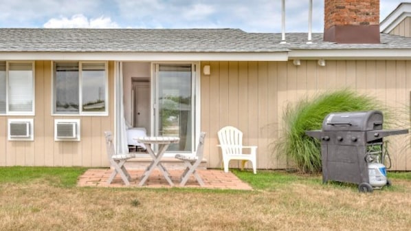 A single-story house with a patio, a grill, and a white chair.