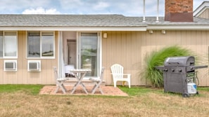 A single-story house with a patio, a grill, and a white chair. - Unit 5 Dbl Queen - Bungalows at Common Ground (Montauk)