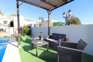 An outdoor patio with a pool, wicker furniture, and a pergola.