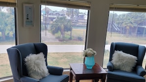 Ein Zimmer mit zwei blauen Sesseln, einem Holztisch und einer Vase mit weißen Blumen.