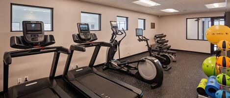 A gym with treadmills, elliptical machines, and exercise balls.