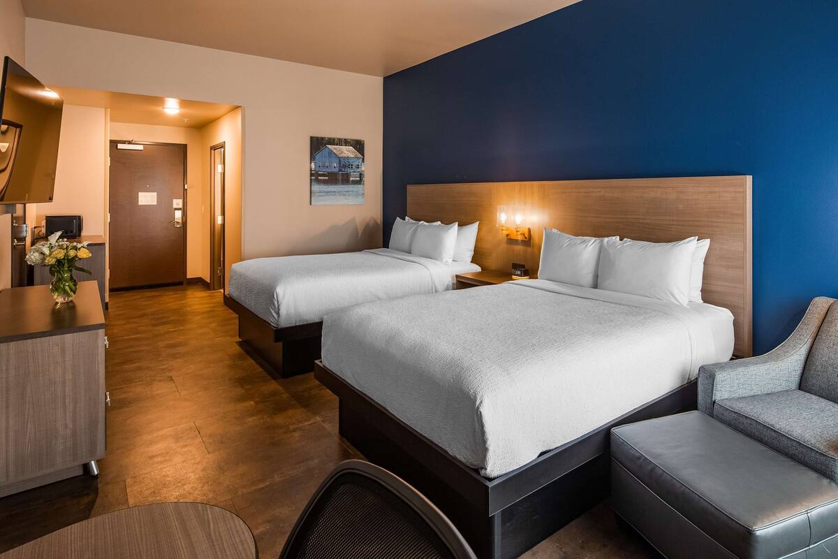 Una habitación de hotel con dos camas, un escritorio, una silla y una mesita.