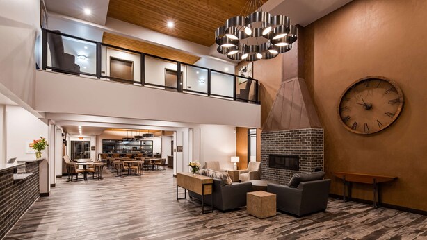 Un hall d’entrée spacieux avec un plafond haut, une cheminée moderne et une grande horloge au mur.