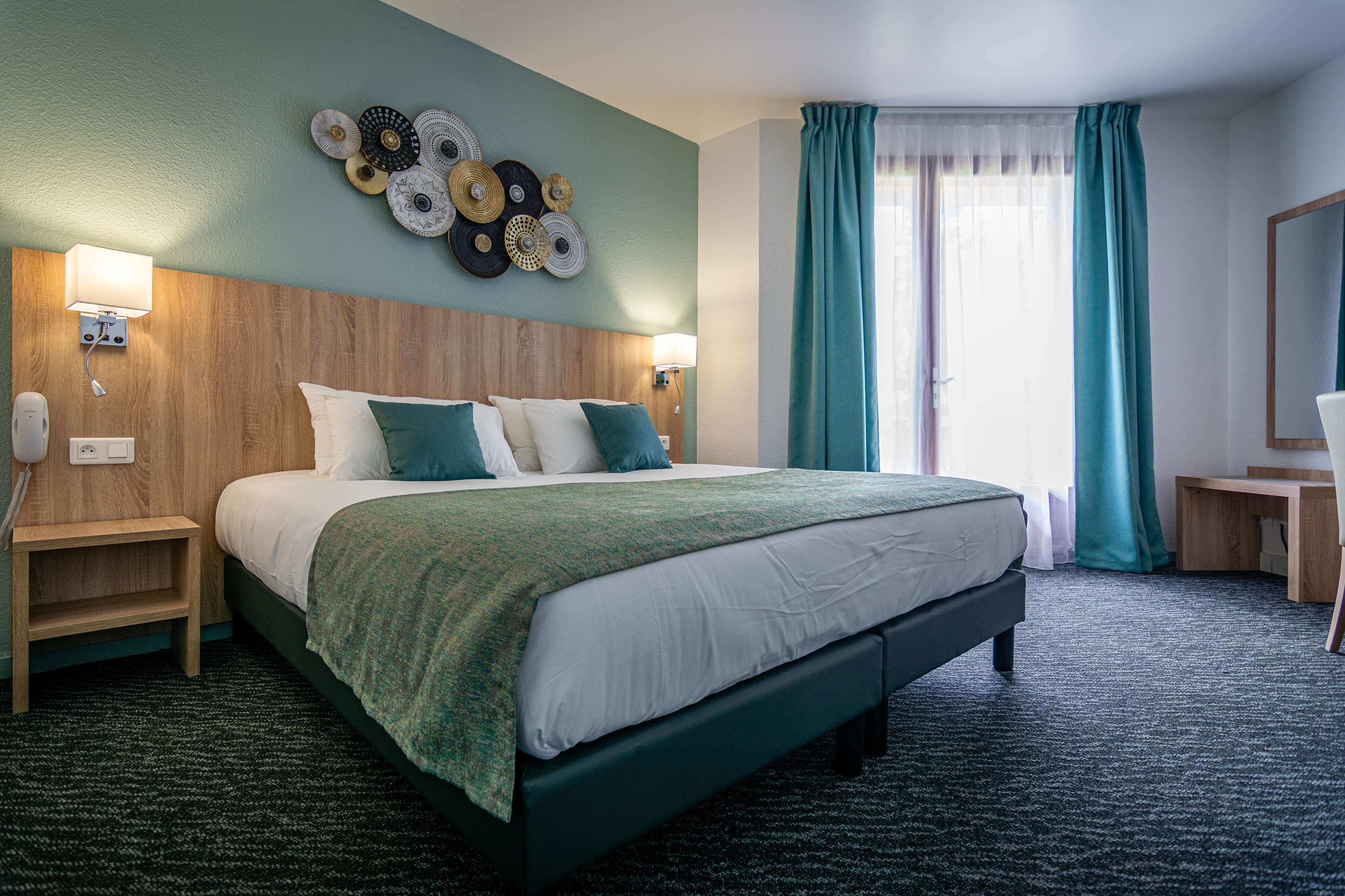 Une chambre d’hôtel avec un grand lit, une tête de lit en bois, une œuvre d’art murale, un bureau et une chaise.