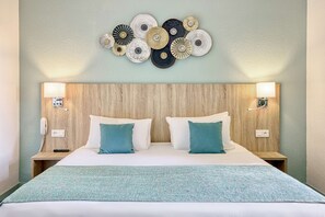 A neatly made bed with two pillows, a wooden headboard, bedside lamps, and a wall decoration above the bed.