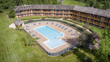 Un hotel grande con piscina rodeada de sillones de descanso.
