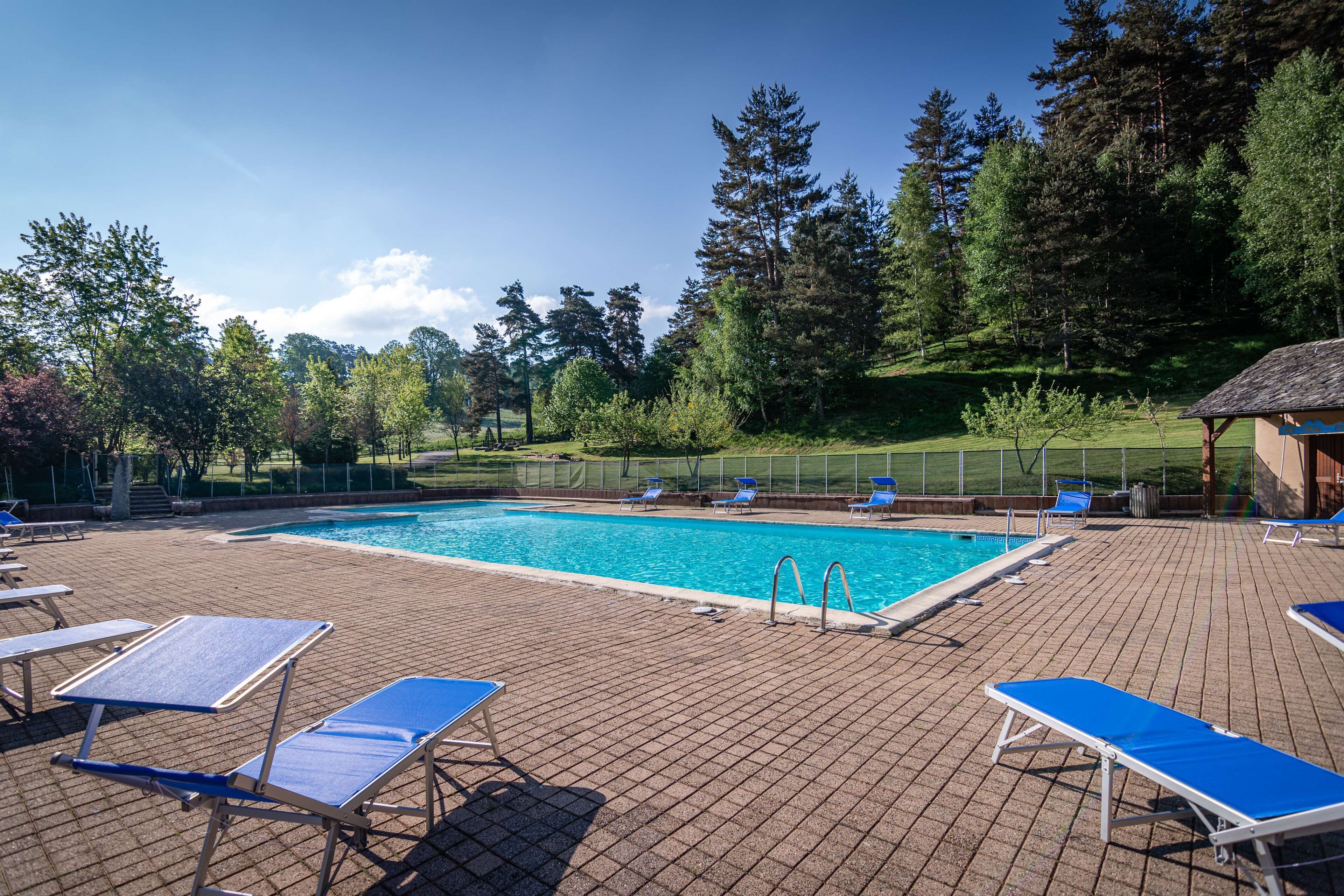 A swimming pool with blue lounge chairs and a brick deck.