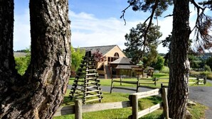Un chalet rustique, doté d’une clôture en bois et d’un escalier en pierre menant à un bâtiment en bois.