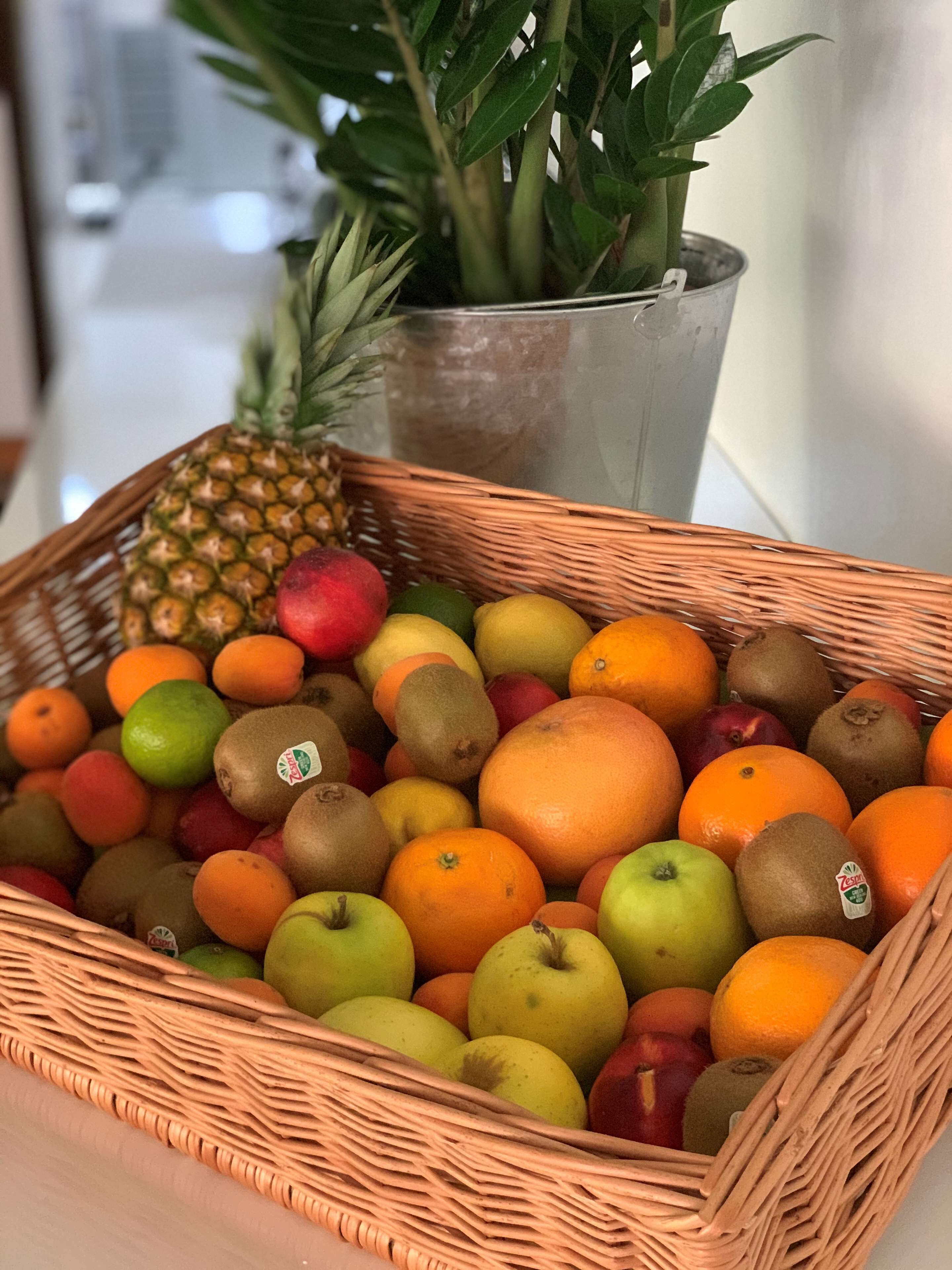 Ein Korankorb, gefüllt mit verschiedenen Früchten, darunter Äpfel, Orangen und Kiwis.
