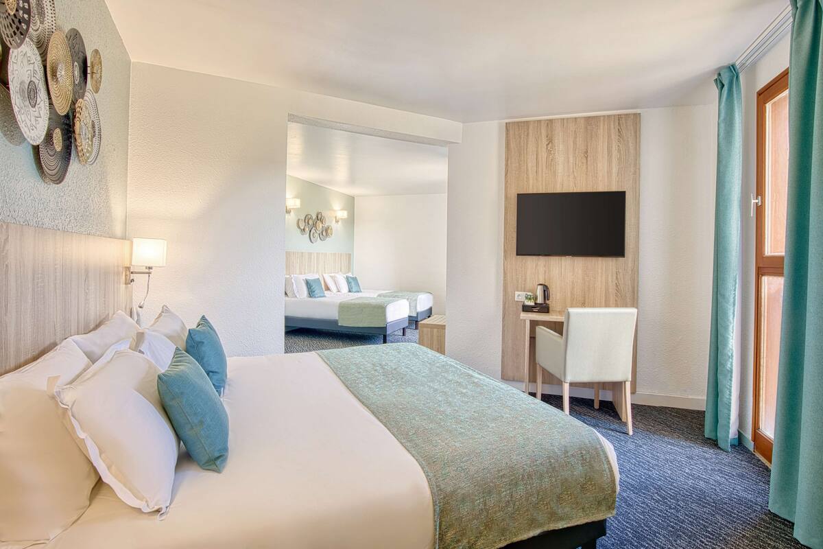 Een hotelkamer met een groot bed, een bureau, een stoel, een flatscreen-televisie en een spiegel.