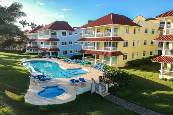 A hotel with a swimming pool, multiple balconies, and a well-maintained lawn. - Gorgeous 2 bed 2 bath beachfront condo in Cabarete (Cabarete)