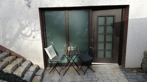 A patio area with a table and chairs, a door with frosted glass panels, and a light fixture on the wall. - Frisch Renoviertes, Lichtdurchflutetes Apartment! (Runkel)