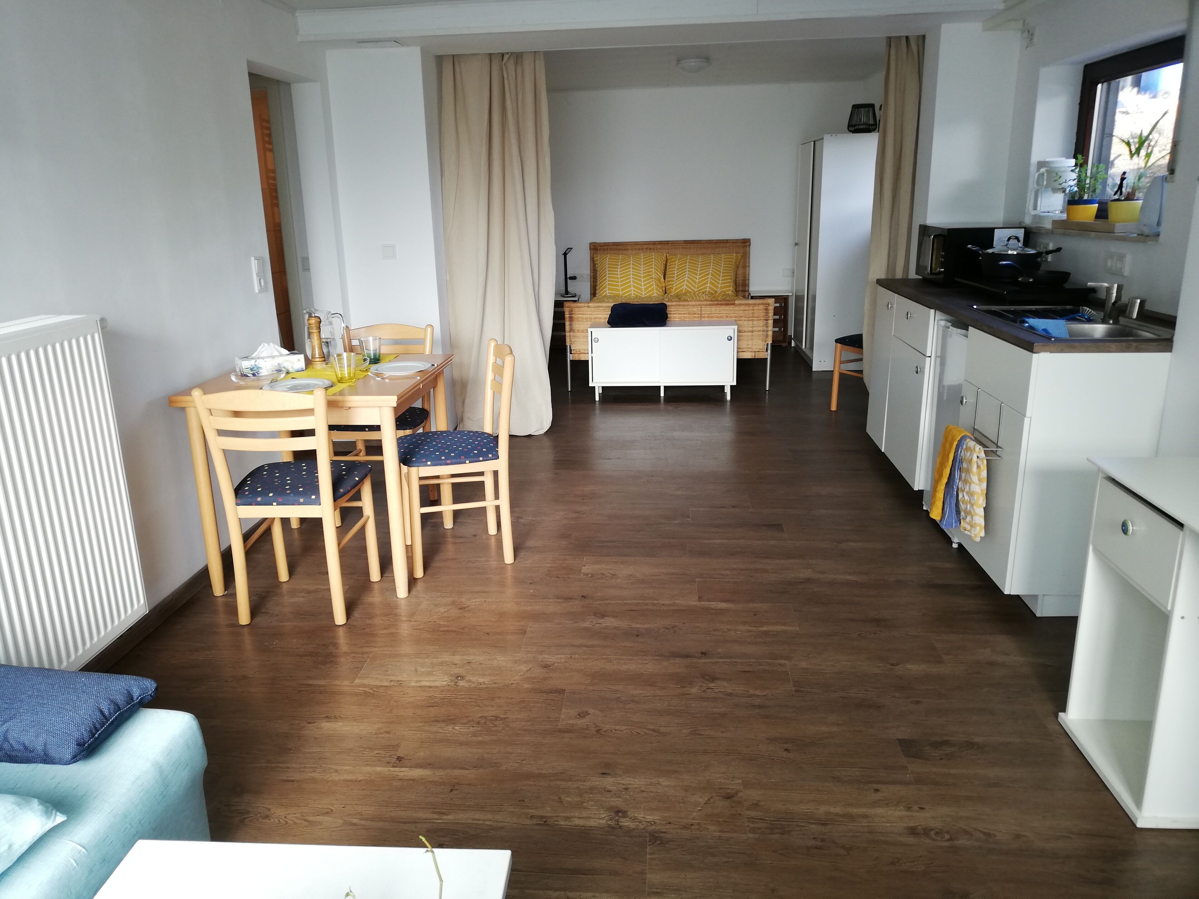 A compact living space with a dining area, kitchenette, and a bed.