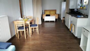 A compact living space with a dining area, kitchenette, and a bed.