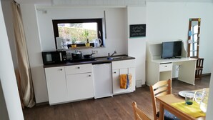 A compact kitchen with white cabinets, a microwave, a kettle, and a small window. - Frisch Renoviertes, Lichtdurchflutetes Apartment! (Runkel)