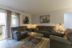 A living room with a leather sofa set, a coffee table, and two lamps. There are two paintings on the wall and a window with curtains. - Western Comfort (Branson)