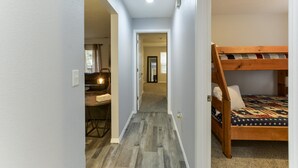 Un couloir étroit, avec un lit superposé sur la droite et un bureau avec une chaise sur la gauche.