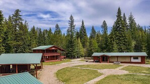 A lodge with a central building and two smaller cabins, surrounded by a forest.