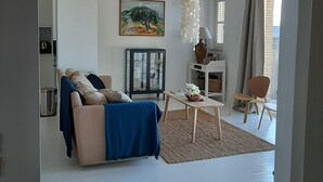 A living room with a sofa, a coffee table, a fireplace, and a painting on the wall.
