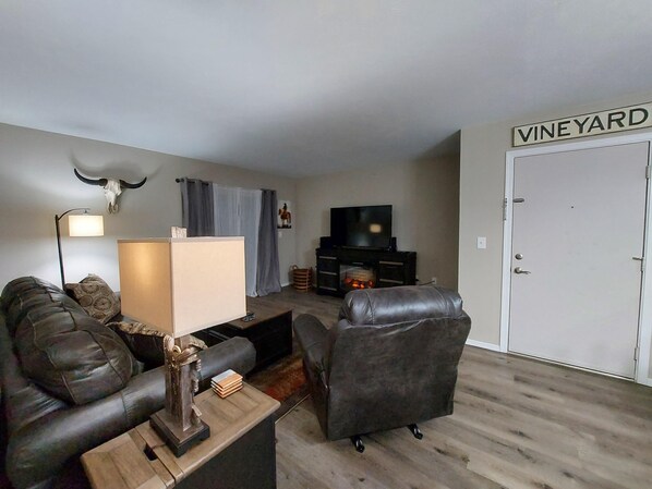A living room with a leather sofa, a coffee table, a TV, and a fireplace.