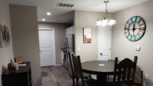 A dining area with a round table, chairs, a chandelier, and a wall clock. - Mystic Ranch Condo (Branson)