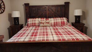 A bed with a plaid bedspread, two bedside lamps, and a headboard with a geometric design. - Mystic Ranch Condo (Branson)
