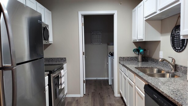A modern kitchen with stainless steel appliances, granite countertops, and white cabinetry.
