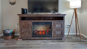 A living room with a fireplace, a television mounted above it, and a floor lamp to the right.