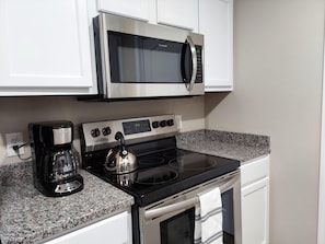 A kitchen with a stainless steel microwave, a coffee maker, and a kettle on the countertop. - Mystic Mountain Condo (Branson)