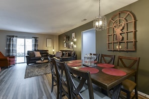 A dining area with a wooden table set for four, surrounded by wooden chairs. - Serenity Now (Branson)