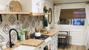 Eine moderne Küche mit weißen Schränken, einer Holz Arbeitsplatte, einem Gasherd und einem Spülbecken.