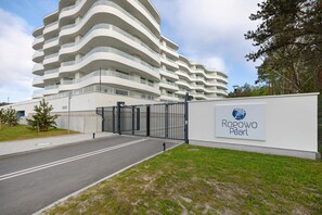 A modern multi-story hotel with a curved facade, a gated entrance, and a sign indicating the name 'Rogowo Pearl.'